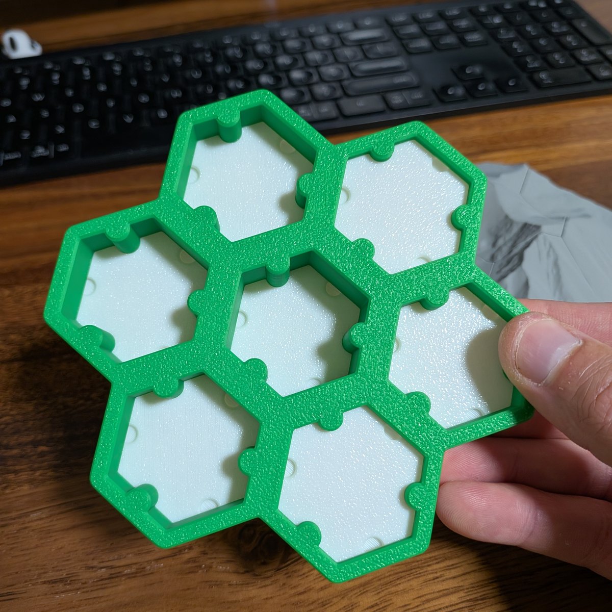 Green hexagonal pedestal with seven tile sockets, held in one hand to show its size