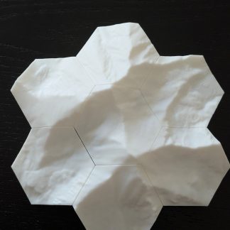 Seven hexagonal topographic tiles assembled into a disc, photographed from directly above on a dark surface